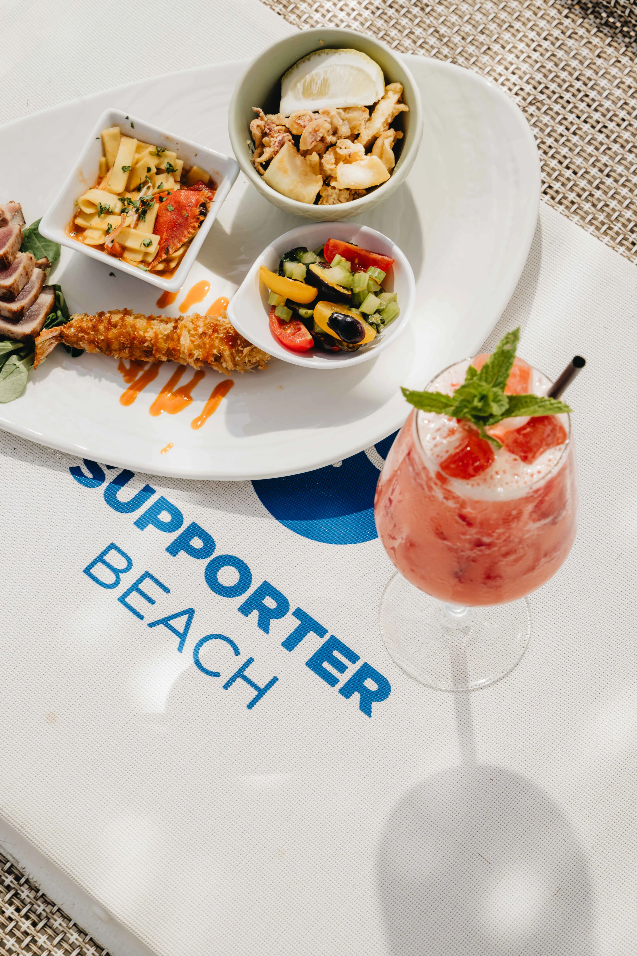 Tavolo con drink, piatti e logo Supporter Beach